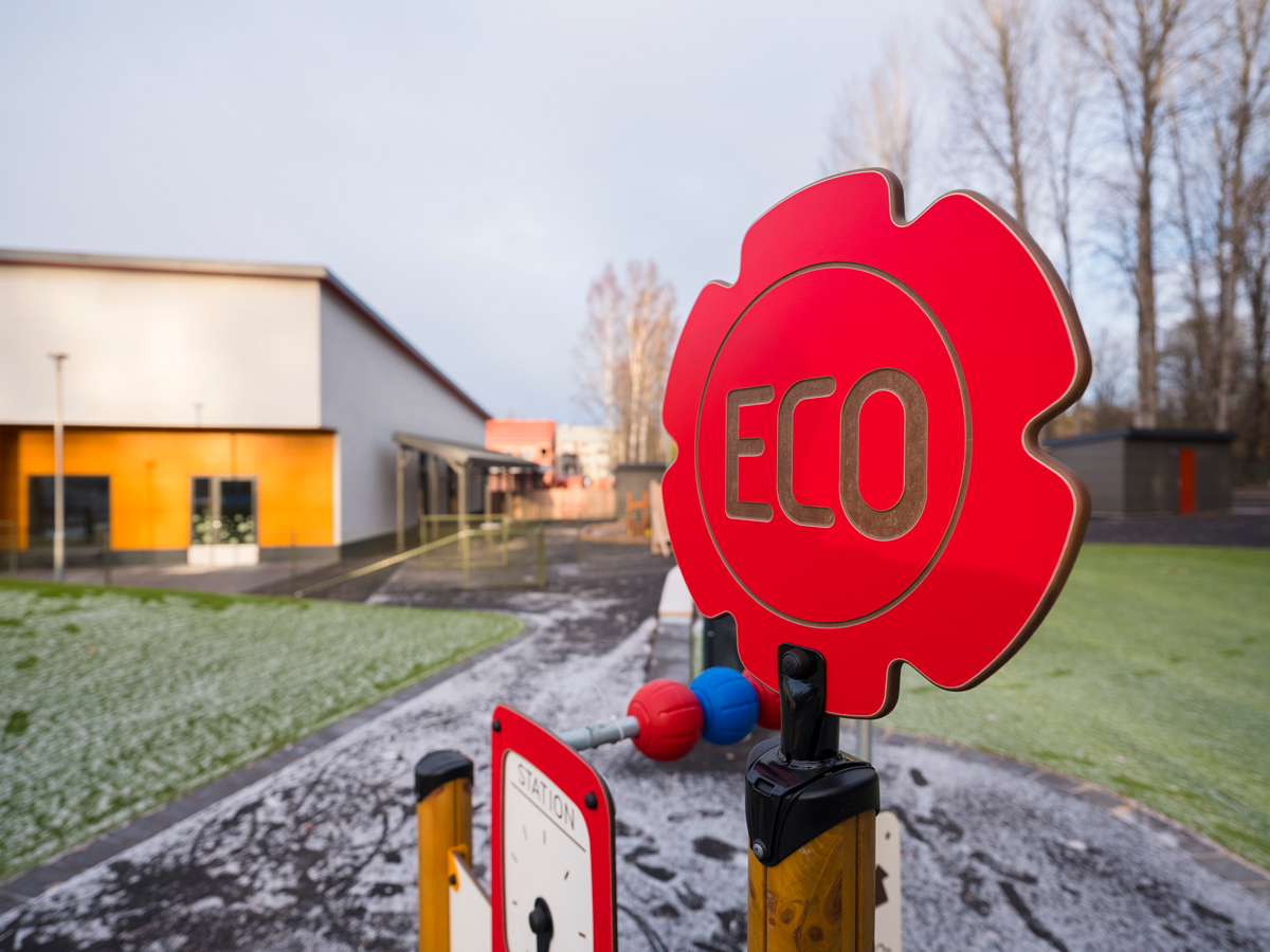 En röd skylt där det står eco, i en skolgårdsmiljö.
