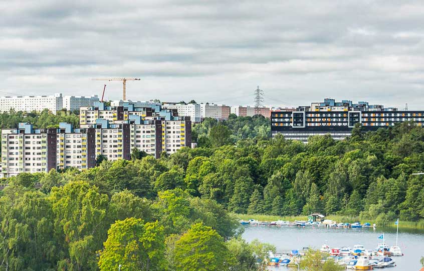 Bild på höghus längs vattnet och båtar i hamn