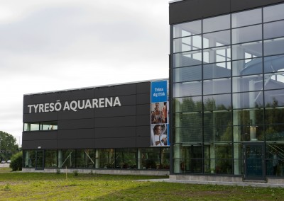 En svart byggnad med en vit skylt: Tyresö Aquarena.