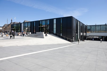 En svart modern byggnad på en öppen plats, Uppsala centralstation.